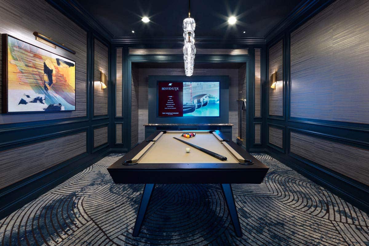 A billiard room with a pool table, a TV, and a painting on the left wall.