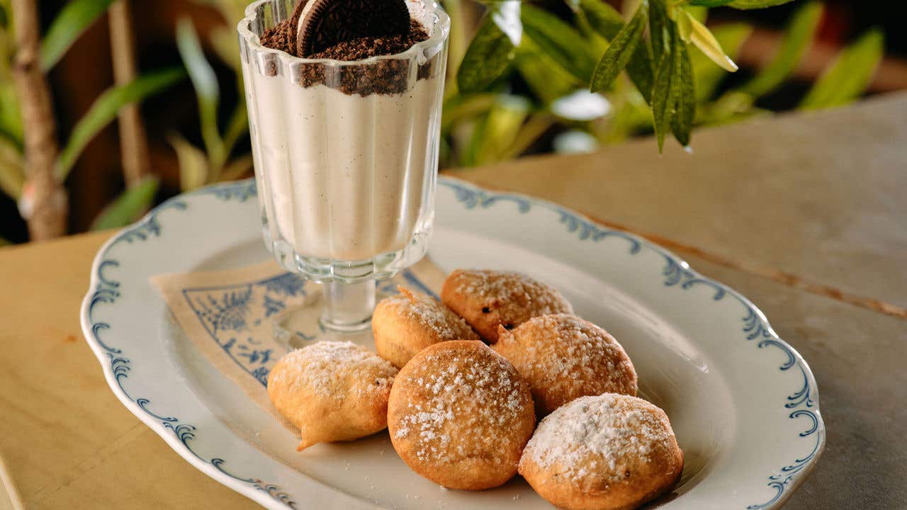 Pastries on a white dish with a milk shake and Oreo cookie in a glass on the same dish.