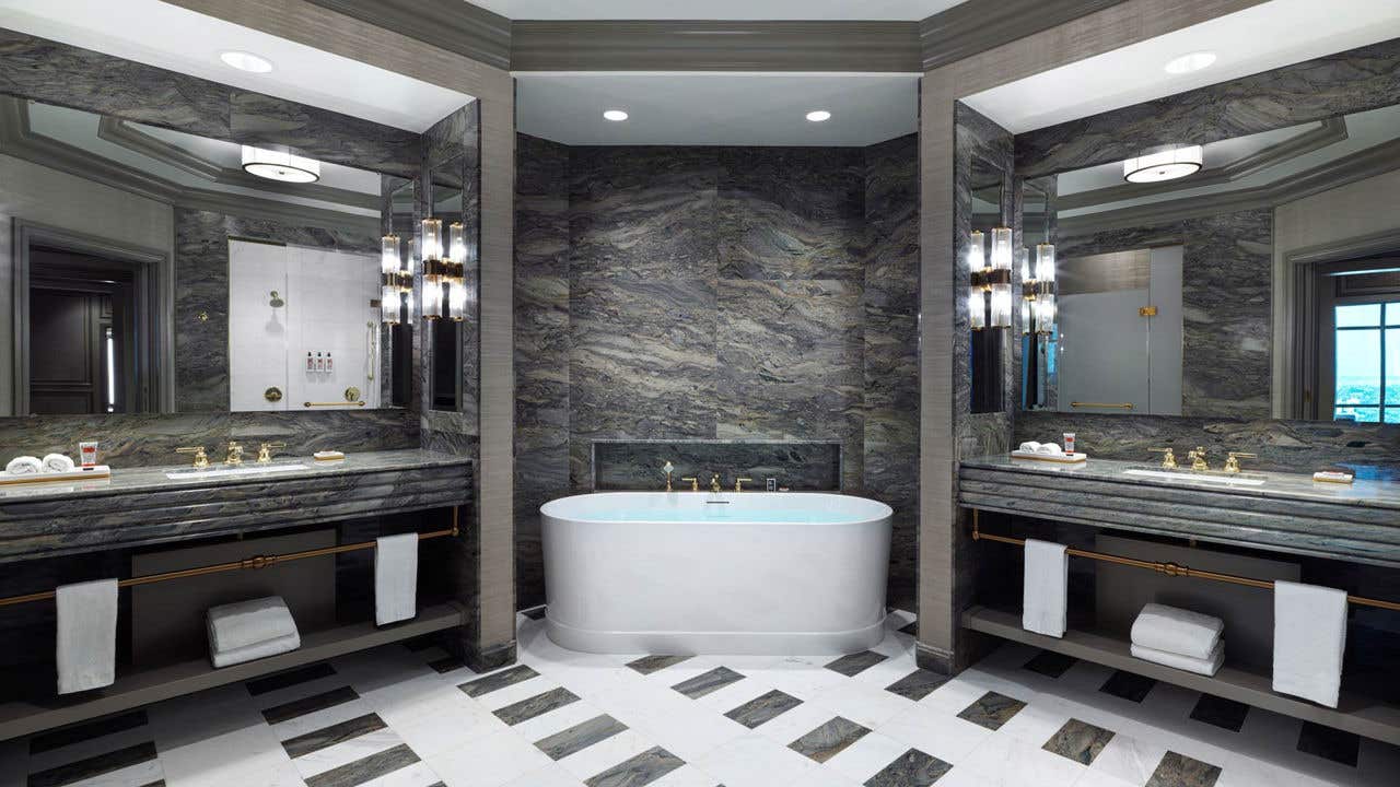 A hotel bathroom with a Roman tub flanked by two separate sink vanities.