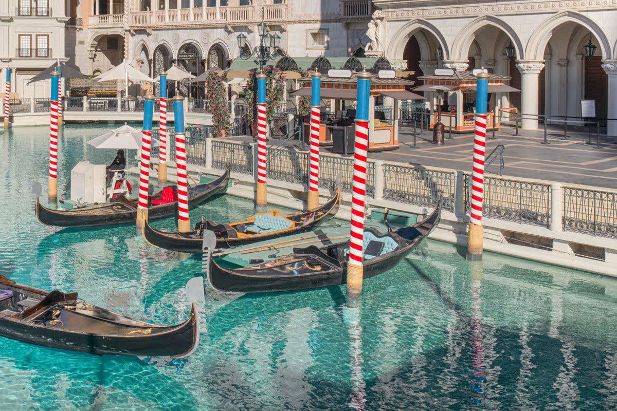 Venetian-style canal with gondolas and striped mooring poles.