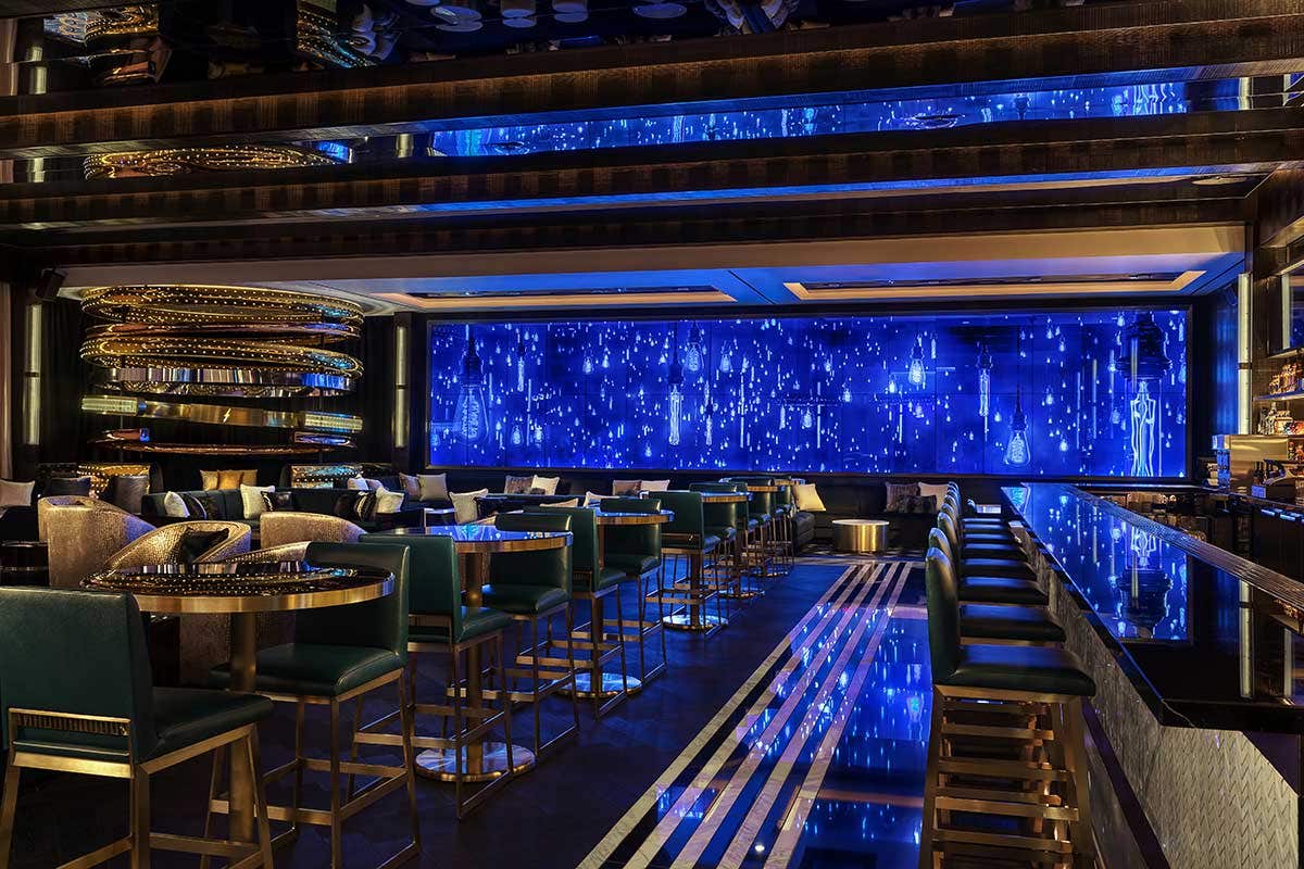 Luxurious bar with blue ambient lighting, sleek seating, and modern decor.