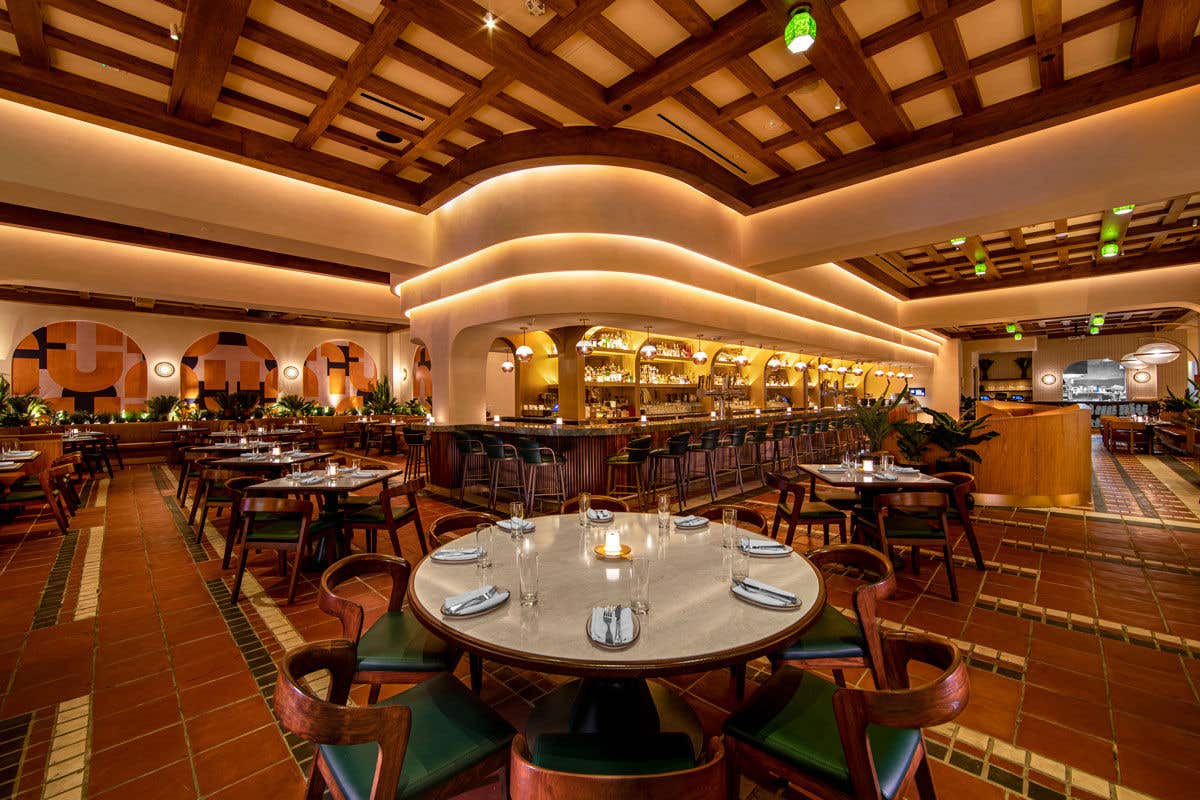 Interior of Las Vegas restaurant Sugarcane, showing a center bar and dark wood tables with green accents.