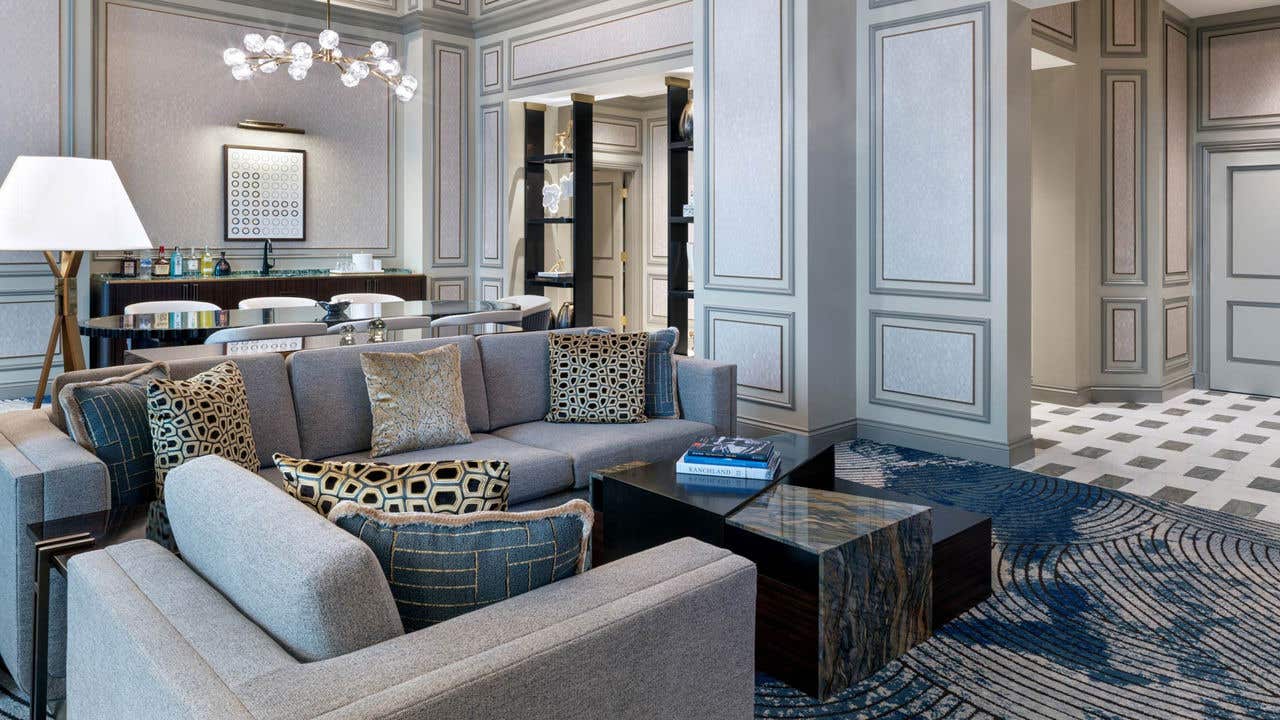 A hotel living room with a couch, coffee table, and dining table.