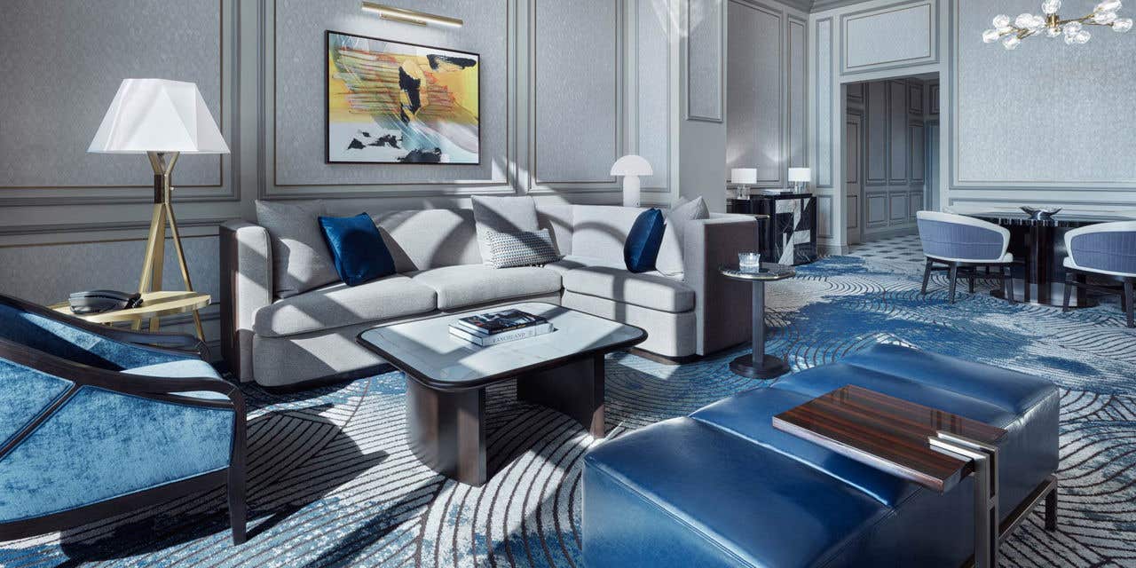 A hotel living room with a couch, coffee table, armchair, bench, and a dining table with four chairs.