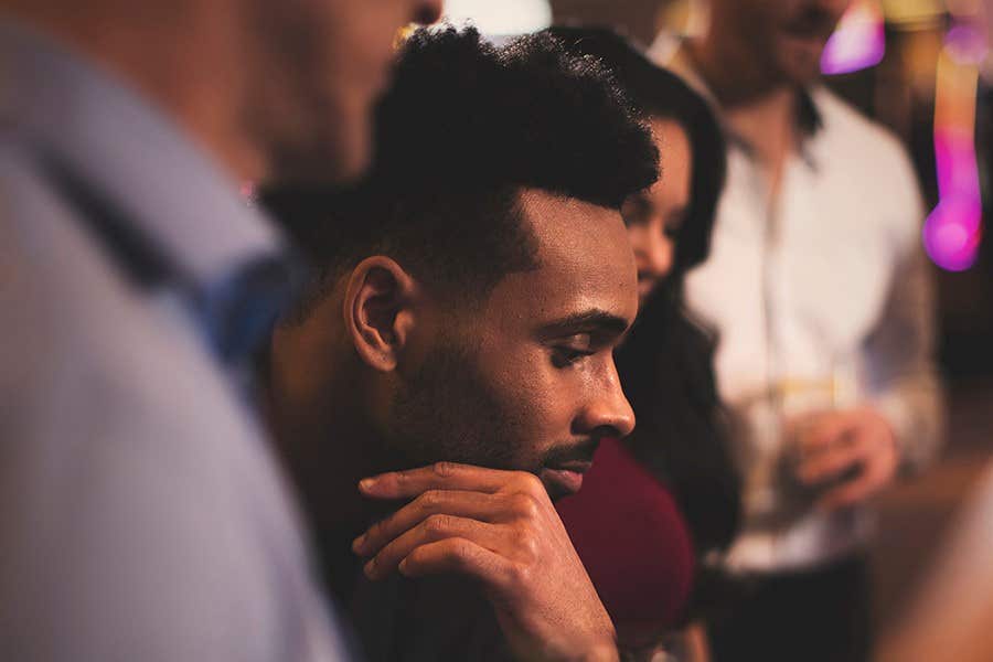 Man focused at casino table, three other people partially visible in background, ambient lighting.
