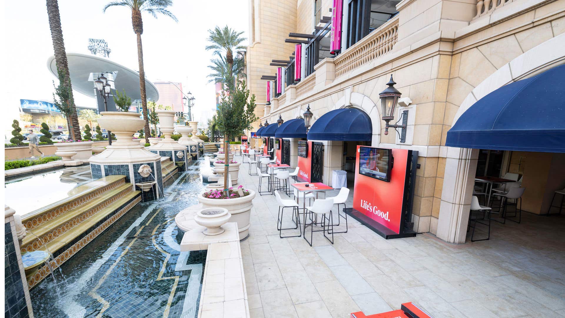 Outdoor patio area with fountain and table seating with white barstools. 