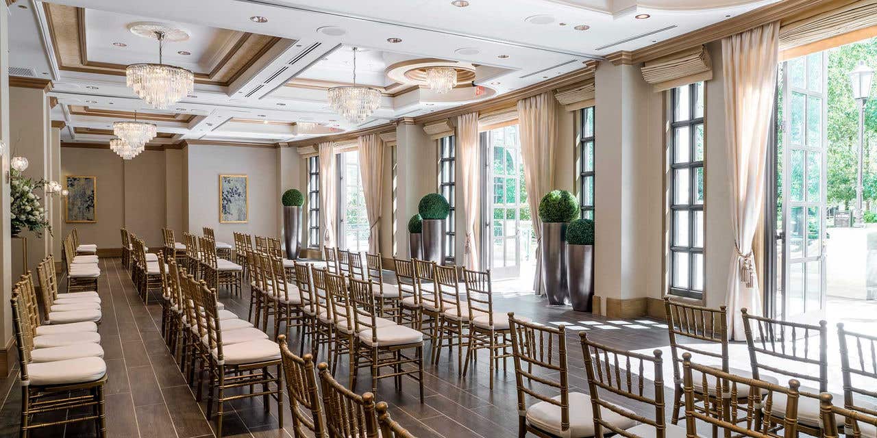 A room with rows of chairs set up and doors open to an outdoor terrace. 