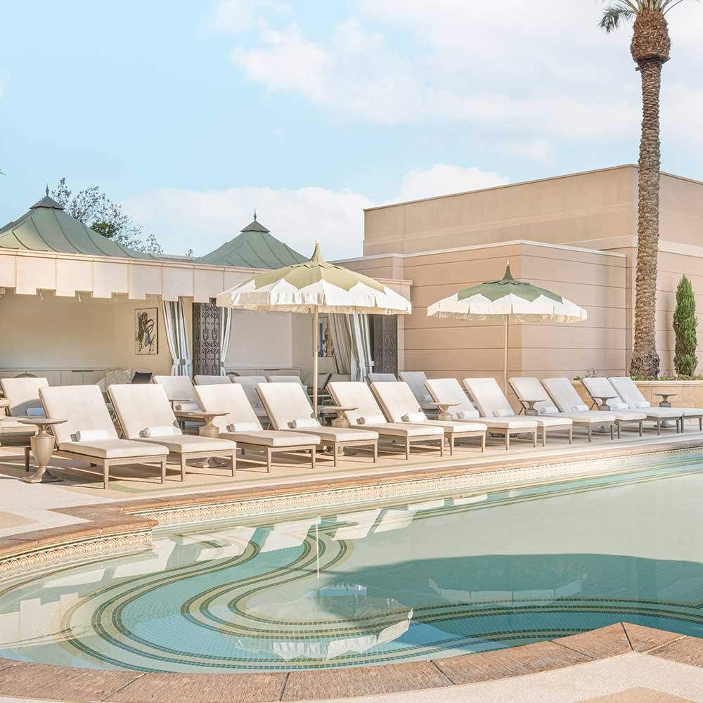 The Palazzo Pool Deck with lounge chairs and umbrellas, set against a blue sky.