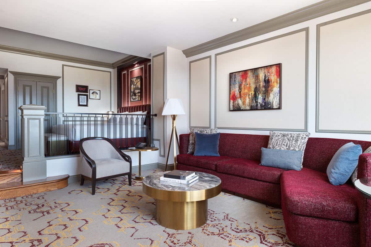 A hotel room with a king bed and a sunken living room with a seating area.