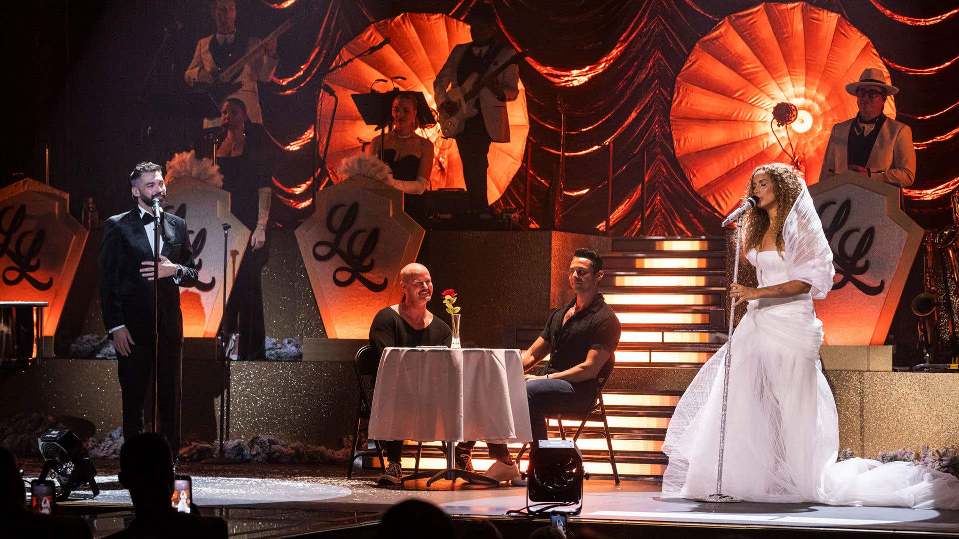 Leona Lewis in a dramatic white tulle gown performing a duet during her concert at The Venetian Resort Las Vegas with a couple seated at a romantic table setup.